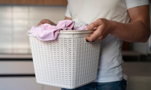 Close-up of hands preparing to wash a bra in a tub, showcasing the gentle process of hand-cleaning delicate lingerie.