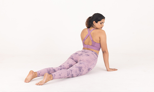 A woman in vibrant purple yoga pants stretches into a downward dog pose, embodying grace and focus during her practice.