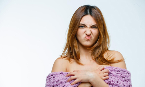 A woman displaying a rash on her chest, highlighting common causes of breast itching and skin irritation.