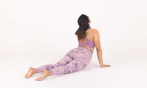 A woman in purple yoga pants performs a downward dog pose, showcasing flexibility and strength in a serene setting.