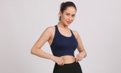 A woman models a blue Razorback Seamless Sports Bra, showcasing its stylish design and comfortable fit.